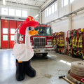 Prints & Giggles 3D goose figurine wearing a red firefighter helmet and black boots inside a fire station.
