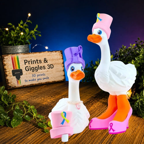 Prints & Giggles 3D whimsical goose figurines wearing purple and pink hats with awareness ribbons and elegant shoes.